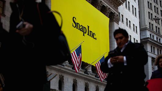 Pedestrians pass in front of Snap Inc. signage displayed on the exterior of the New York Stock Exchange (NYSE) during the company's initial public offering (IPO) in New York, U.S., on Thursday, March 2, 2017.