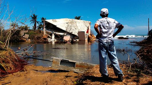 A man surveys a house that was washed away by heavy surf during the passing of Hurricane Maria in Manati, Puerto Rico on October 6, 2017.