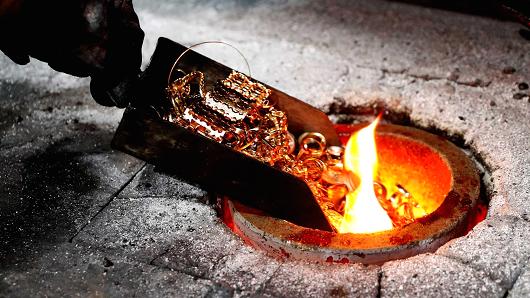 A worker places gold jewelery into a melting furnace at the Austrian Gold and Silver Separating Plant in Vienna, Austria.
