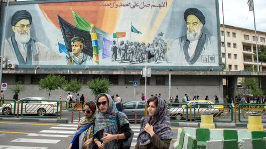 Women cross a street near a giant political mural depicting Ayatollah Ali Khamenei, Iran's supreme leader, left, and Ruhollah Khomeini, founder of the Islamic republic of Iran, in Tehran, Iran, on Wednesday, May 9, 2018.