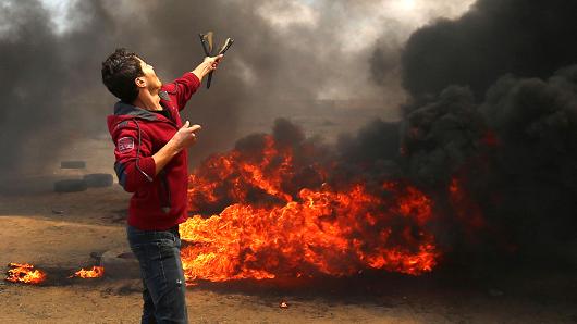 A Palestinian man uses a slingshot during clashes with Israeli forces along the border with the Gaza strip east of Khan Yunis on May 14, 2018, as Palestinians protest over the inauguration of the US embassy following its controversial move to Jerusalem.