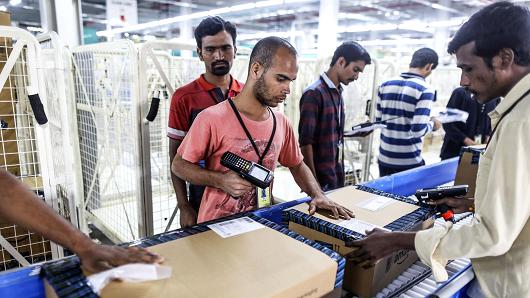 Employees prepare packages for shipment on the conveyor belt at the Amazon.com fulfillment center in Hyderabad, India.