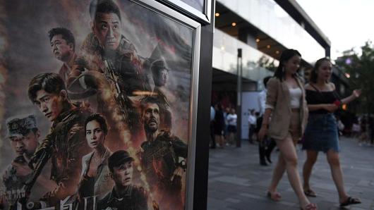 People walk by a movie poster for Chinese action flick "Wolf Warrior 2" in Beijing, China.