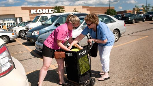 Customers pull a dinnerware set from a shopping cart outside of a Kohl's store in Peru, Illinois.