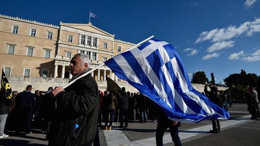 A farmer holds a Greek flag in front of parliament during a protest against the government's tax and social security reforms on February 14, 2017 in Athens, Greece.