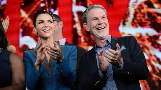 Reed Hastings, chief executive officer of Netflix Inc., right, applauses during a news conference in Tokyo, Japan.