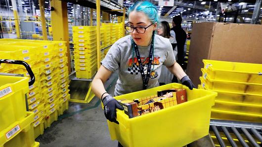 A worker moves a bin filled with products inside of an Amazon fulfillment centre in Robbinsville, New Jersey, November 27, 2017.