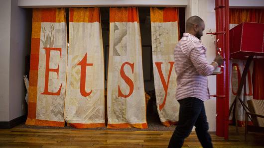 An employee walks past a quilt displaying Etsy Inc. signage at the company's headquarters in the Brooklyn.