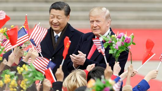 President Donald Trump, right, and Xi Jinping, China's president, greet attendees waving American and Chinese national flags during a welcome ceremony outside the Great Hall of the People in Beijing, China, on Thursday, Nov. 9, 2017.