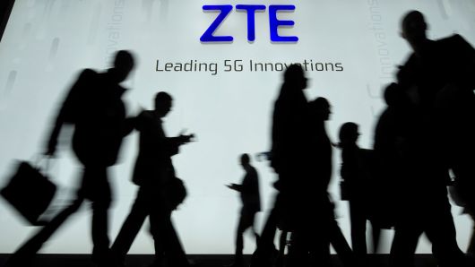 People walk in front of the ZTE stand at the Mobile World Congress on February 27, 2018 in Barcelona.