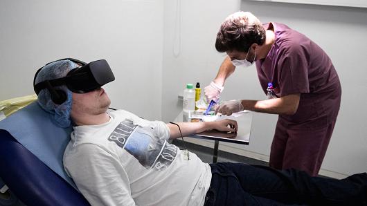 A nurse treats a patient wearing the 3D therapeutic virtual reality headset developed by Healthy Mind start-up, at the emergency service department of the Saint-Joseph Hospital in Paris, France, June 7, 2018.