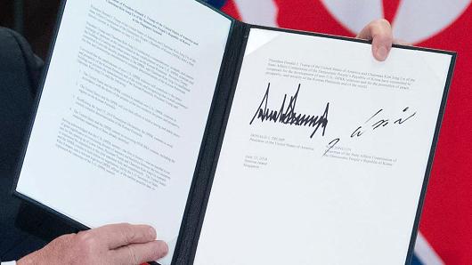 US President Donald Trump holds up a document signed by him and North Korea's leader Kim Jong Un following a signing ceremony during their historic US-North Korea summit, at the Capella Hotel on Sentosa island in Singapore on June 12, 2018.