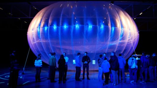 Visitors stand next to a high altitude WiFi internet hub, a Google Project Loon balloon, on display at the Air Force Museum in Christchurch, New Zealand, on June 16, 2013.
