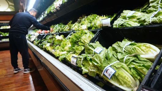 A man shops for vegetables beside Romaine lettuce stocked and for sale at a supermarket in Los Angeles.