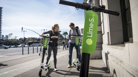 People use a smartphone to unlock LimeBike shared electric scooters on the Embarcadero in San Francisco.
