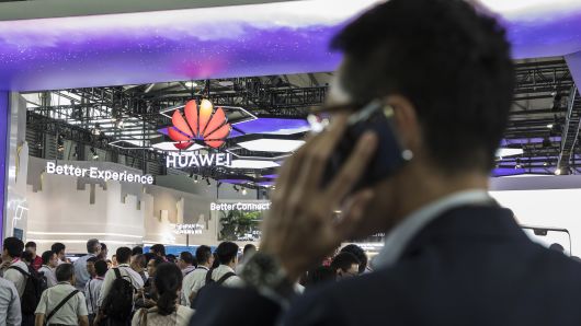An attendee uses a mobile phone while standing in front of the Huawei Technologies Co. booth at the Mobile World Congress Shanghai in Shanghai, China, on Thursday, June 28, 2018. The exhibition runs through June 29. 