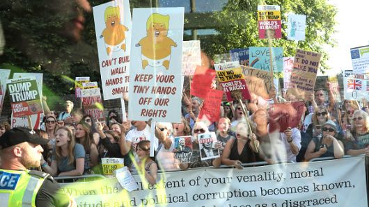 Protesters seen from a coach window hold up placards along the route at Blenheim Palace prior the arrival of U.S. President Donald Trump and First Lady Melania Trump on July 12, 2018 in Woodstock, England.