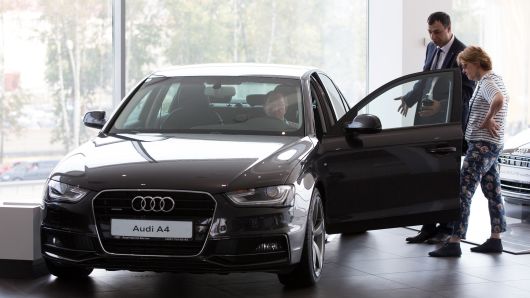 A car dealer assists customers with an Audi A4 automobile at an Audi AG showroom in Moscow, Aug. 2, 2014.