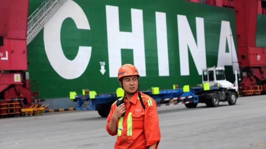 A docker works in front of a container ship at Qingdao Port in Qingdao, Shandong Province of China.