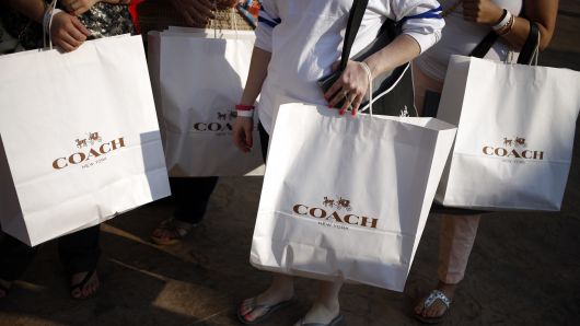 Customers carry Coach Inc. shopping bags after shopping at a store during a charity preview event on the eve of the grand opening of the Outlet Shoppes of The Bluegrass in Simpsonville, Kentucky.