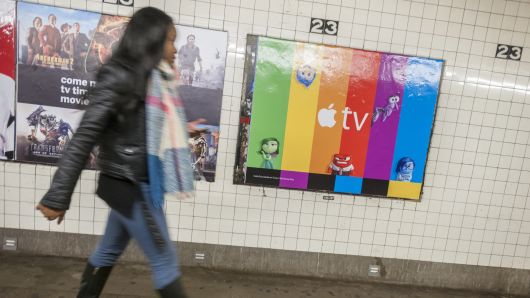 A commuter walks past a poster advertising the AppleTV streaming video product, next to a Hulu ad, in the subway in New York.
