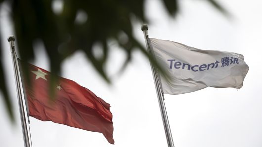 A flag bearing the Tencent logo is displayed alongside a Chinese flag outside the company's offices in Beijing, China.