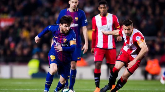 Lionel Messi of FC Barcelona runs with the ball next to Alex Granell of Girona FC during the La Liga match between Barcelona and Girona at Camp Nou on February 24, 2018 in Barcelona, Spain.