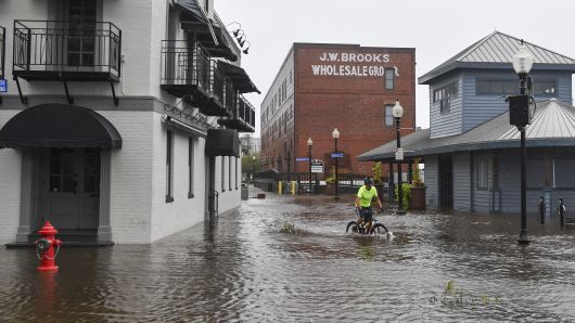A bicyclist rides through a flooded South Water Street as Hurricane Florence makes landfall on September 14, 2018 in Wilmington, NC.