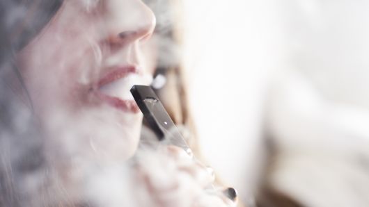 A person smokes a Juul Labs e-cigarette in this arranged photograph taken in the Brooklyn, New York.