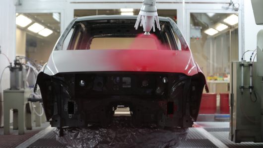 A robotic arm sprays red paint onto an automobile body at PPG Industries Inc.'s automotive coating's technical center in Ingersheim, Germany.