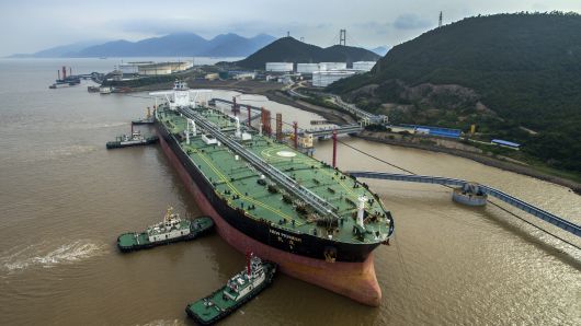 An oil tanker sits beside transfer pipes at a terminal as it prepares to unload its cargo of fuel on July 4, 2018 in Zhoushan, China. 