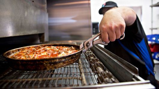 An employee removes a pizza from the oven at a Domino's Pizza restaurant in Rantoul, Illinois.