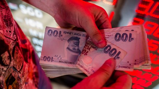 A money changer counts Turkish lira banknotes at a currency exchange office in Istanbul, on August 8, 2018. 