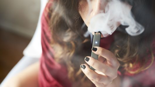 A person smokes a Juul Labs Inc. e-cigarette in this arranged photograph taken in the Brooklyn Borough of New York, U.S., on Sunday July 8, 2018. 
