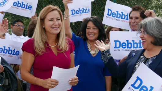 Surrounded by a small group of family and supporters, Democrat Debbie Mucarsel-Powell, left, announces she is running against Republican U.S. Rep. Carlos Curbelo,  outside the West Perrine Health Center in Miami on Wednesday, Aug. 2, 2017. 