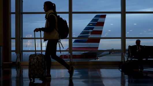 A traveler walks past an American Airlines Group Inc. aircraft at Ronald Reagan National Airport (DCA) in Washington, D.C.