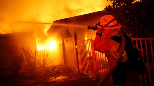 Firefighters try to contain a fire so it doesn't spread to a neighboring building as the Camp Fire moves through the area on November 8, 2018 in Paradise, California. 