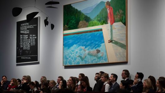 A crowd of people attend the sale where David Hockney's Portrait of an Artist (Pool with Two Figures) is displayed at Christie's in New York.