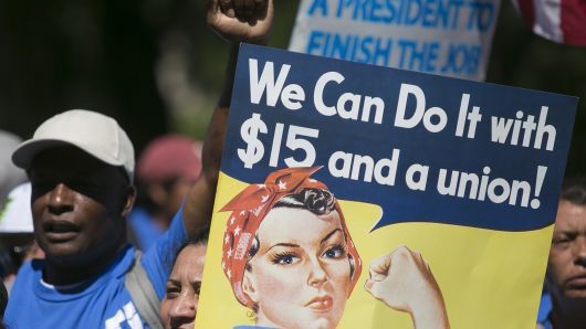 A protester holds a sign in Upper Senate Park during a rally on Capitol Hill in Washington, D.C., on Wednesday, July 22, 2015, to push for a raise to $15 an hour for the minimum wage.