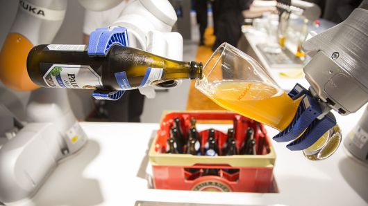A industrial robotic arm pours a glass of beer in Munich, Germany, on Tuesday, June 21, 2016.