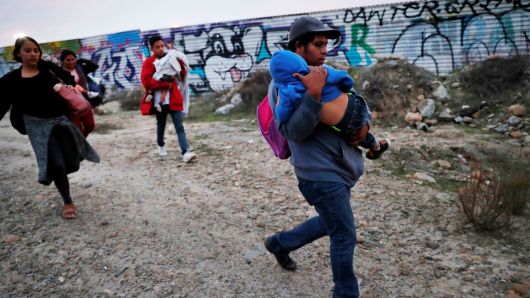 A migrant child sleeps while he is carried by family as fellow migrants, all part of the caravan of migrants who traveled from Central America with the intention of crossing into the U.S., walk to the border fence in order to cross into the U.S. from Tijuana, Mexico December 14, 2018.