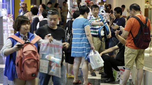 A group of Chinese tourists stand with shopping bags at the Canal City Hakata commercial complex in Fukuoka, Japan, on Friday, July 24, 2015. Four million Chinese tourists are expected to head to Japan this year.