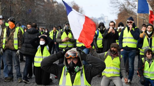 Protestors wearing 'yellow vests' (gilet jaune) kneel on the Champs Elysees avenue in Paris on December 8, 2018 during a protest against rising costs of living they blame on high taxes. 