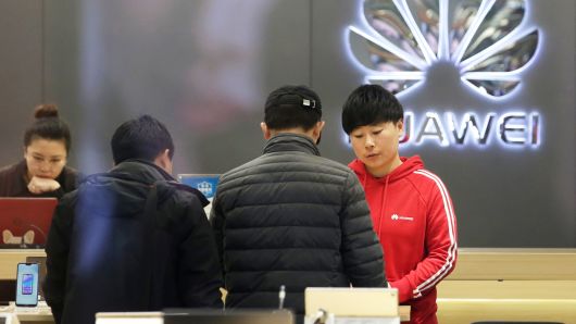 A saleswoman serves customers at a Huawei shop in Beijing, China, December 12, 2018.