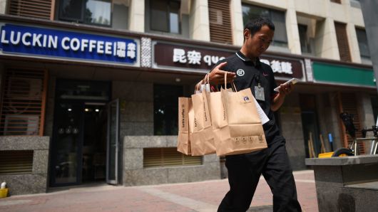 A deliveryman carrying bags of coffee walks out a Luckin Coffee in Beijing on August 2, 2018.