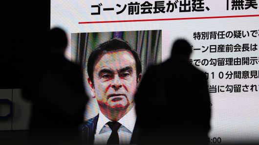 Pedestrians walk past a big screen showing images of Former Nissan Motor Co. Chairman Carlos Ghosn in a news program on Jan. 8, 2019 in Tokyo, Japan.
