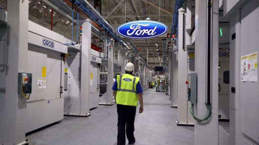 An employee walks past a Ford logo in the yet-to-be-completed engine production line at a Ford factory on January 13, 2015 in Dagenham, England.