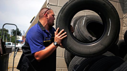A mechanic stacks used tires outside the service bay of a Goodyear Tire & Rubber Co. auto garage in Shelbyville, Kentucky.
