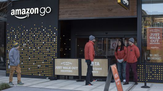Employees stand outside the new Amazon Go grocery store in Seattle, Washington, U.S., on Tuesday, Dec. 6, 2016.
