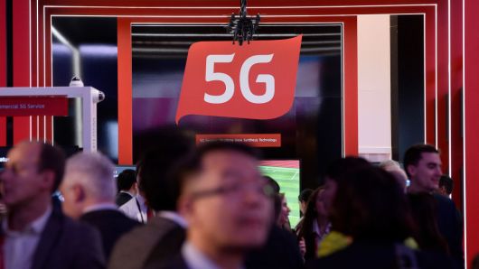 People walk by a 5G stand at the Mobile World Congress (MWC), the world's biggest mobile fair, on February 26, 2018 in Barcelona.
